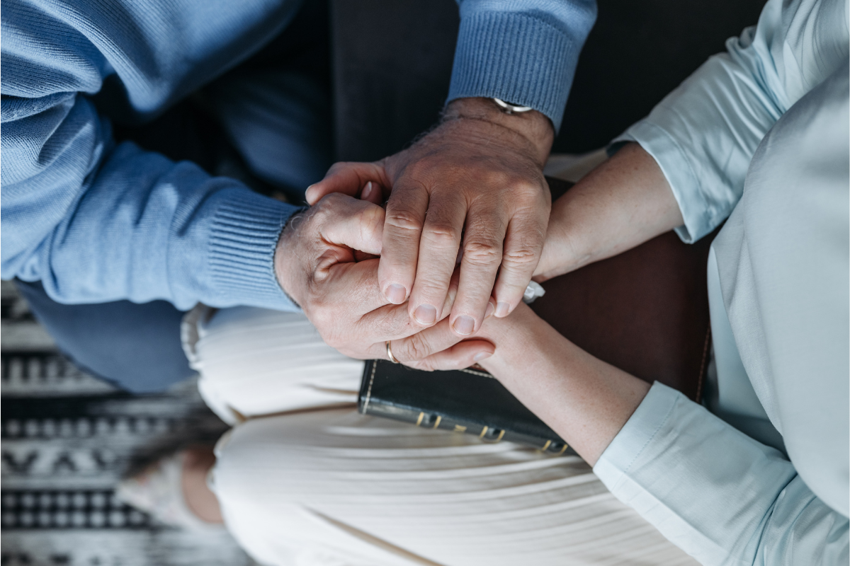 Image of a man holding a woman's hands for a blog post covering common funeral expenses.