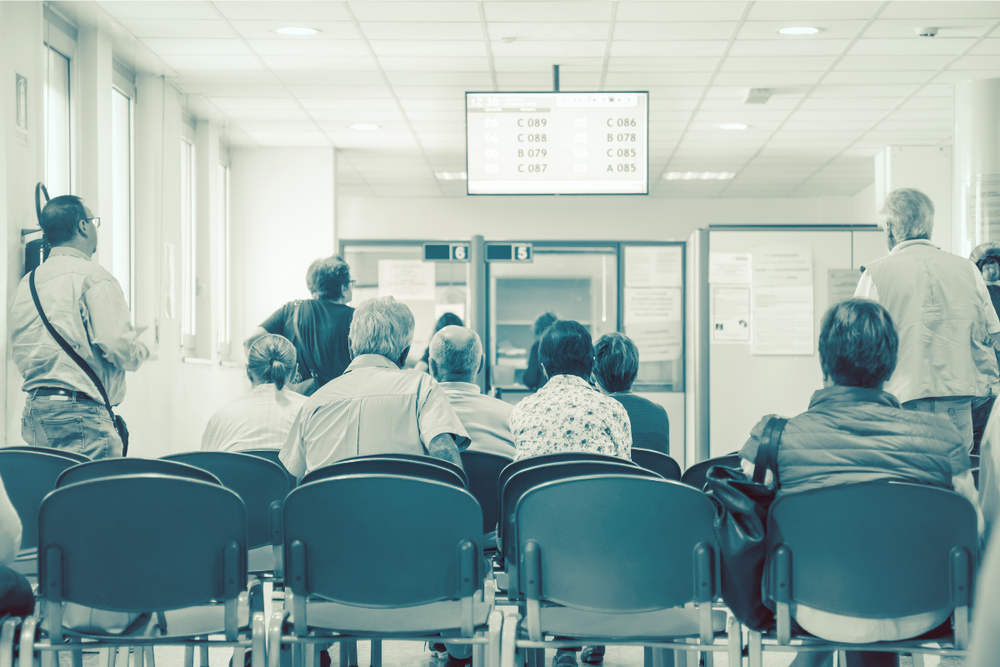 Image of people at the DMV waiting for their number to be called for a blog post on how to report a death to the DMV.