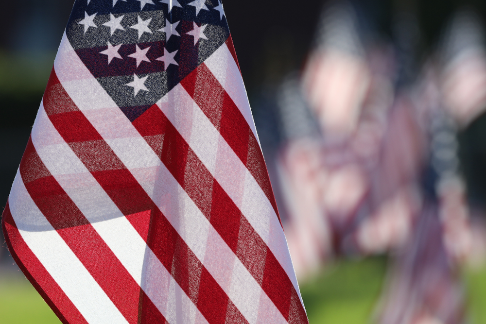 Image of several small American flags in a grass field for a post about understanding Veterans Administration death benefits.
