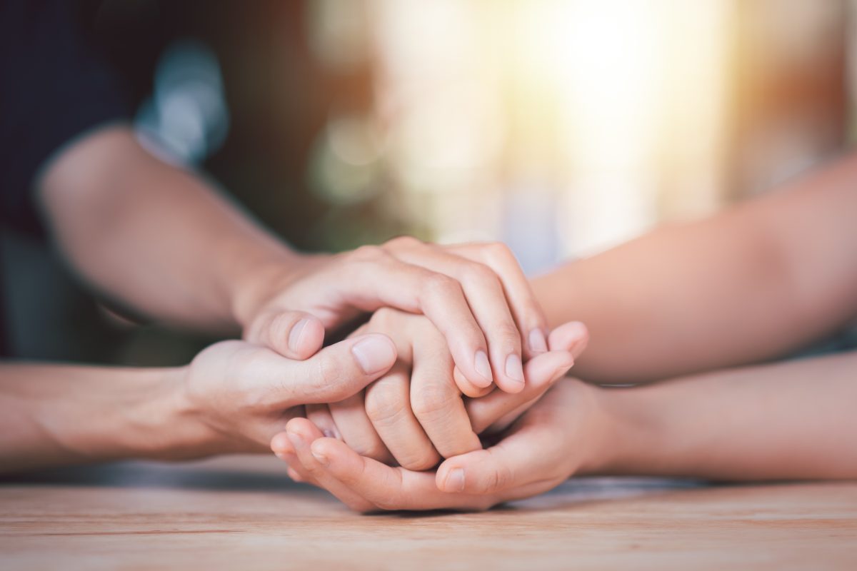 Image of two people clasping hands together on a tabletop for a blog post about choosing a funeral home.