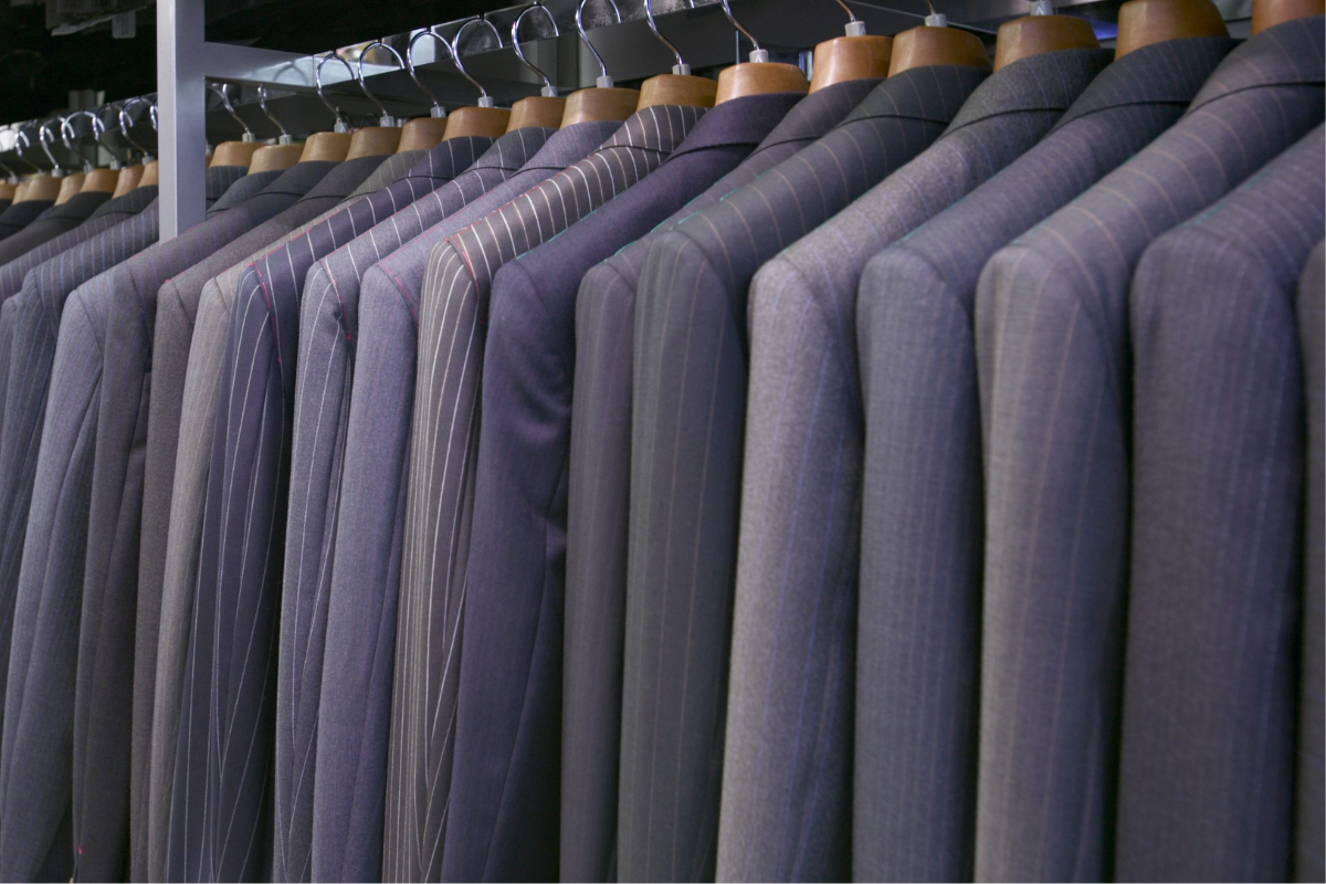 Image of dark suits on a rack for a blog post answering the question "What do pallbearers wear."