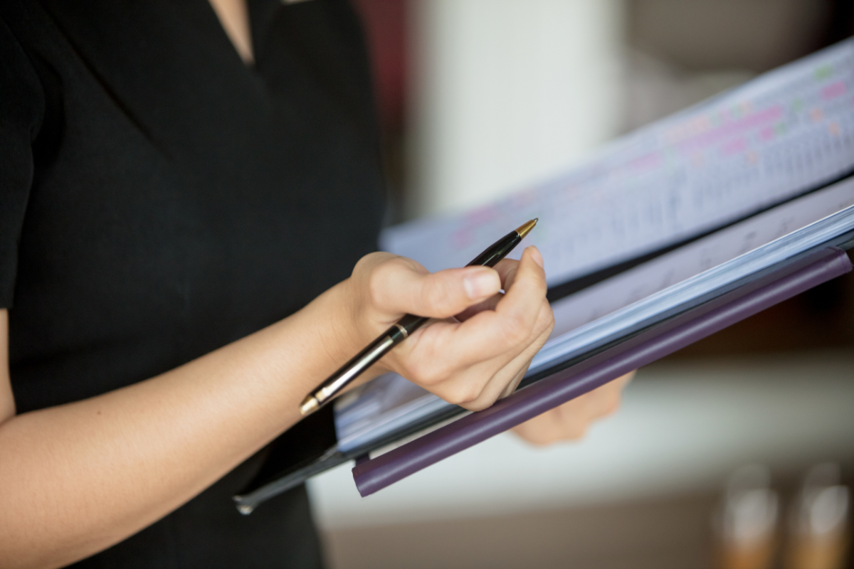 Image of a woman updating a death notification checklist for a recently deceased family member.