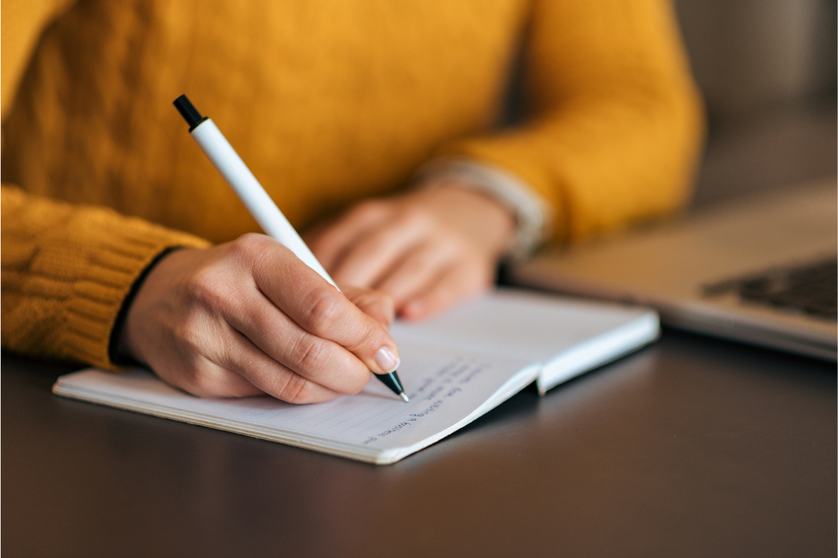 Image of a woman at a desk to write an obituary