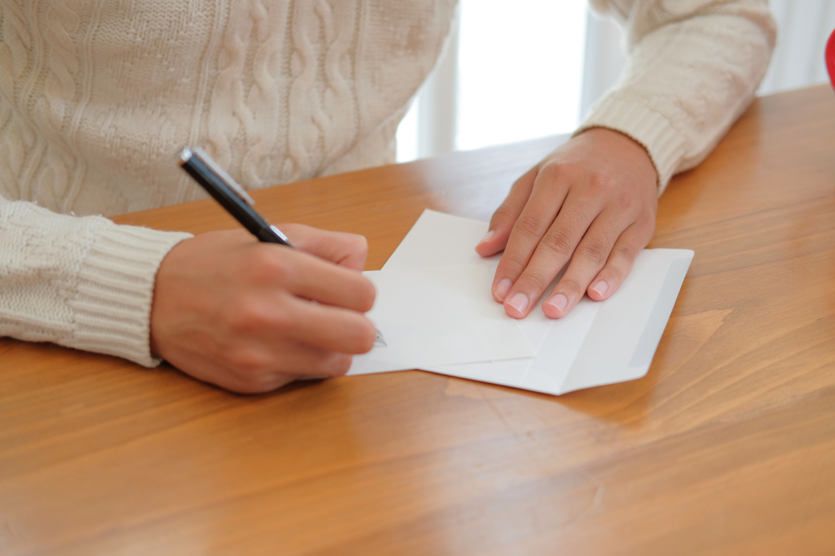 Image of a woman writing a note at a desk for a blog post about how to write a message of condolence.